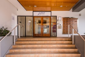 A reception area with a wooden ceiling, a reception desk, and a staircase leading to the upper floors. - Quest On Nelson (Auckland)