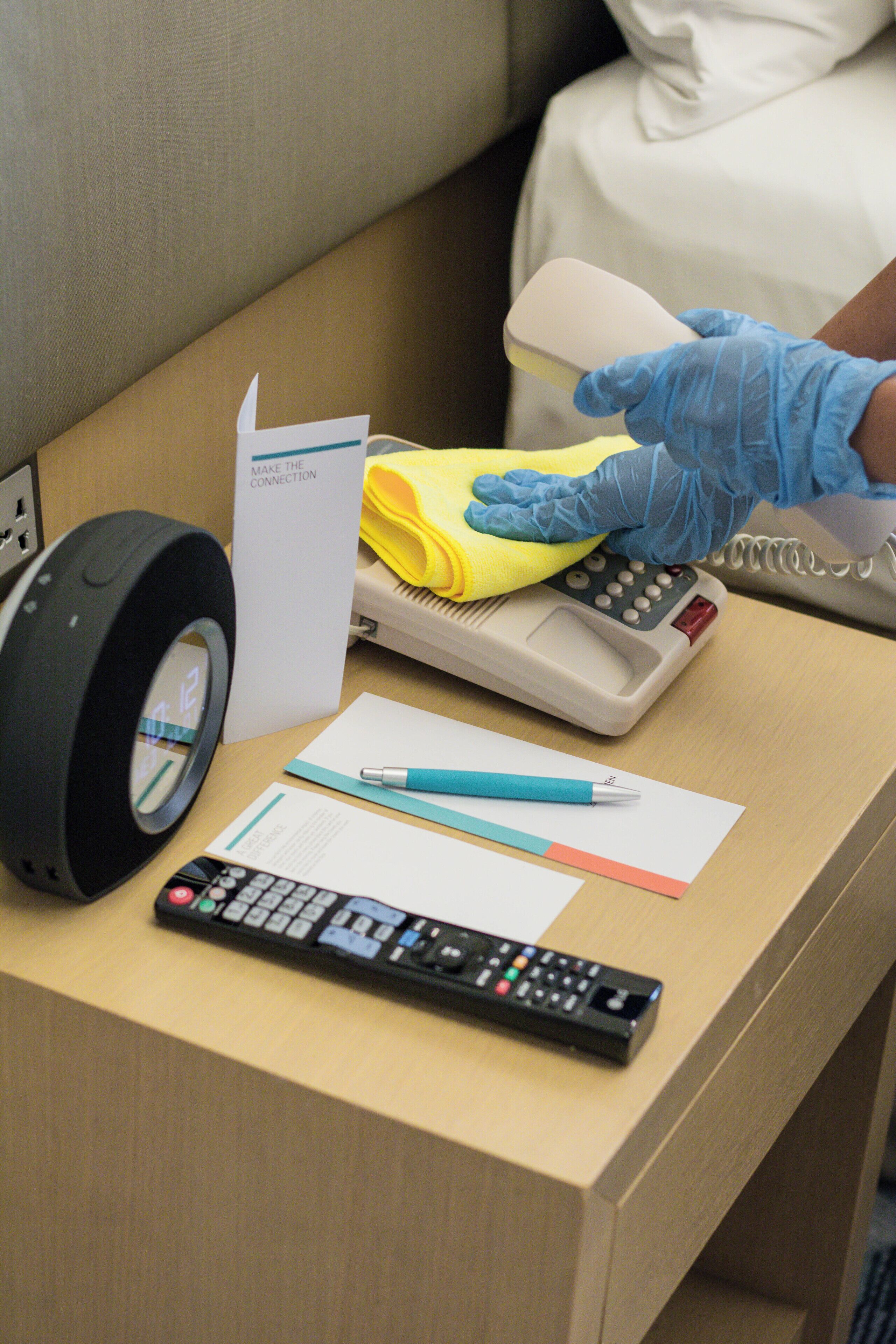 A desk with a remote control, a calculator, a yellow cloth, a pen, and a sign that reads "MAKE THE CONNECTION".