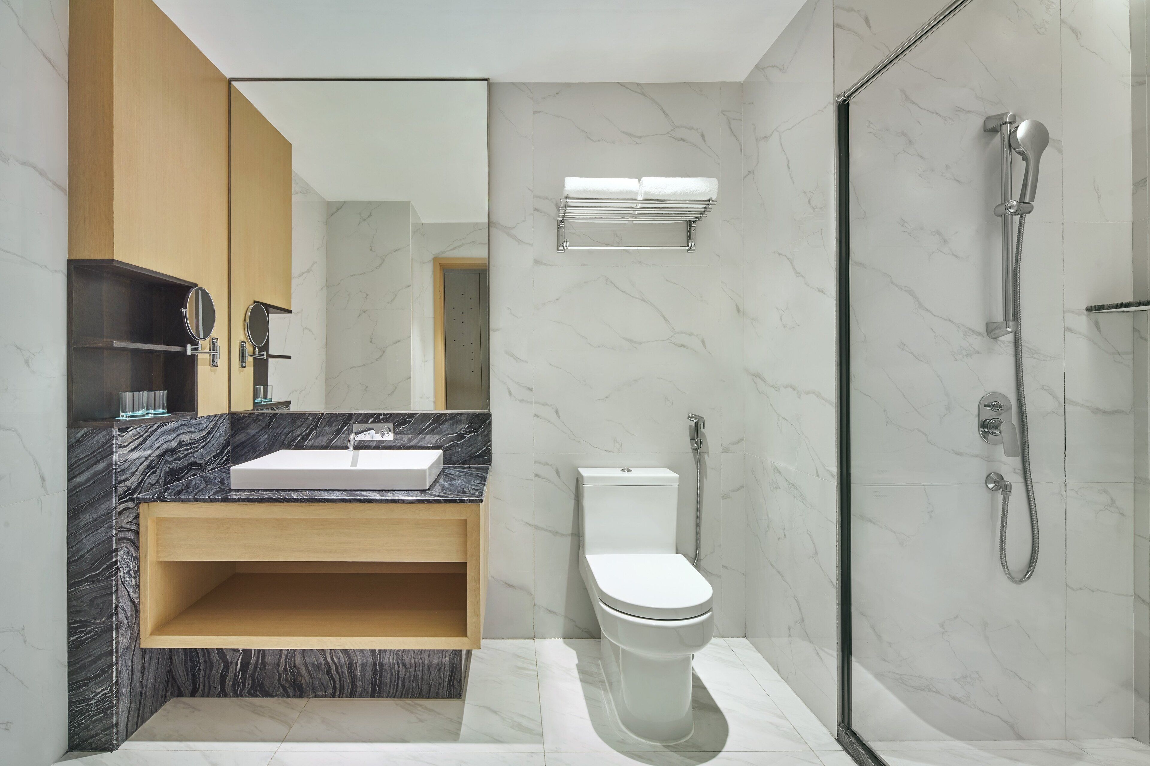 Een moderne badkamer met een marmeren wastafel, een houten opbergmeubel en een douche met glazen wanden.