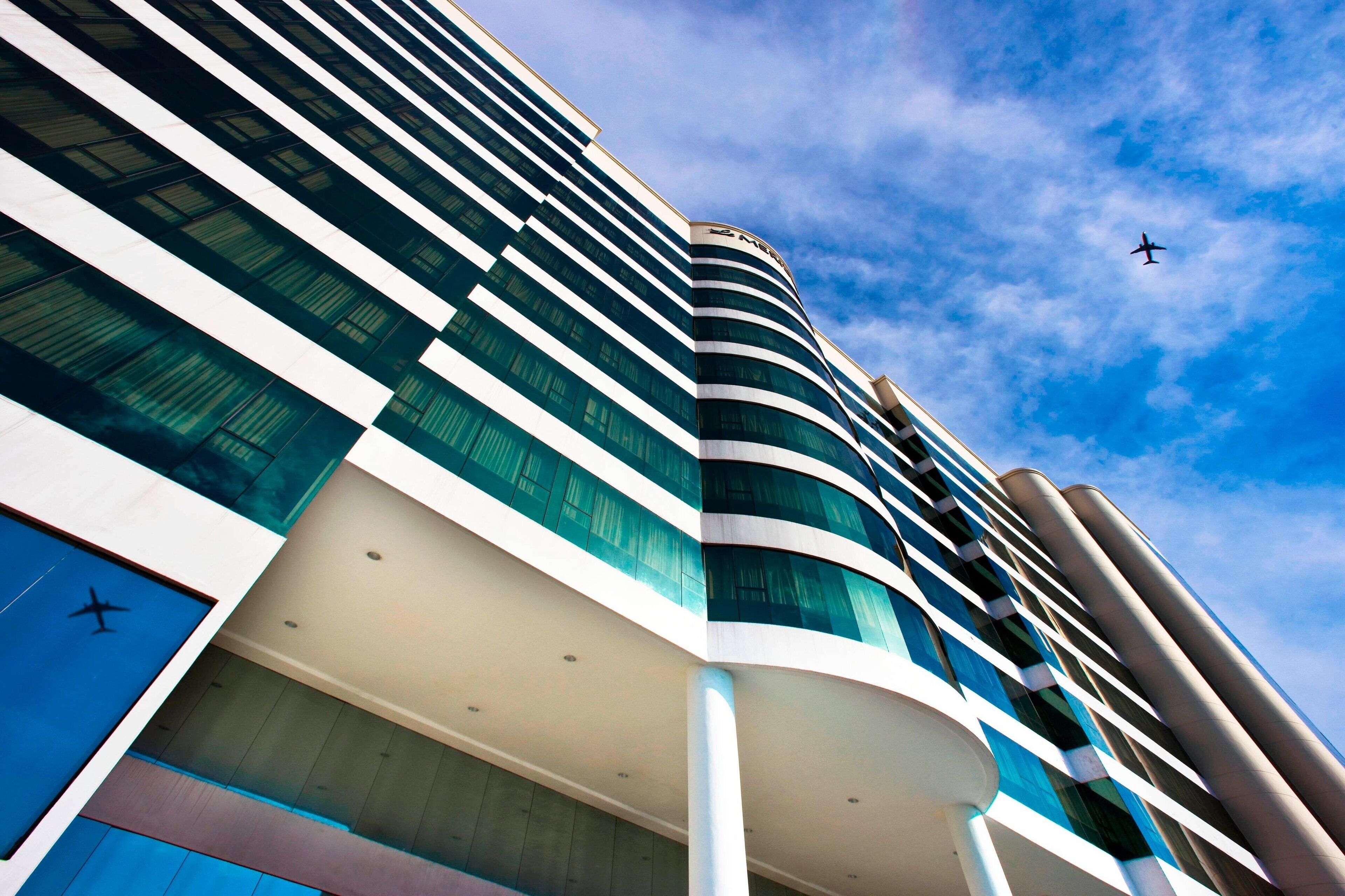 A modern hotel with a curved facade, large windows, and a pool area.