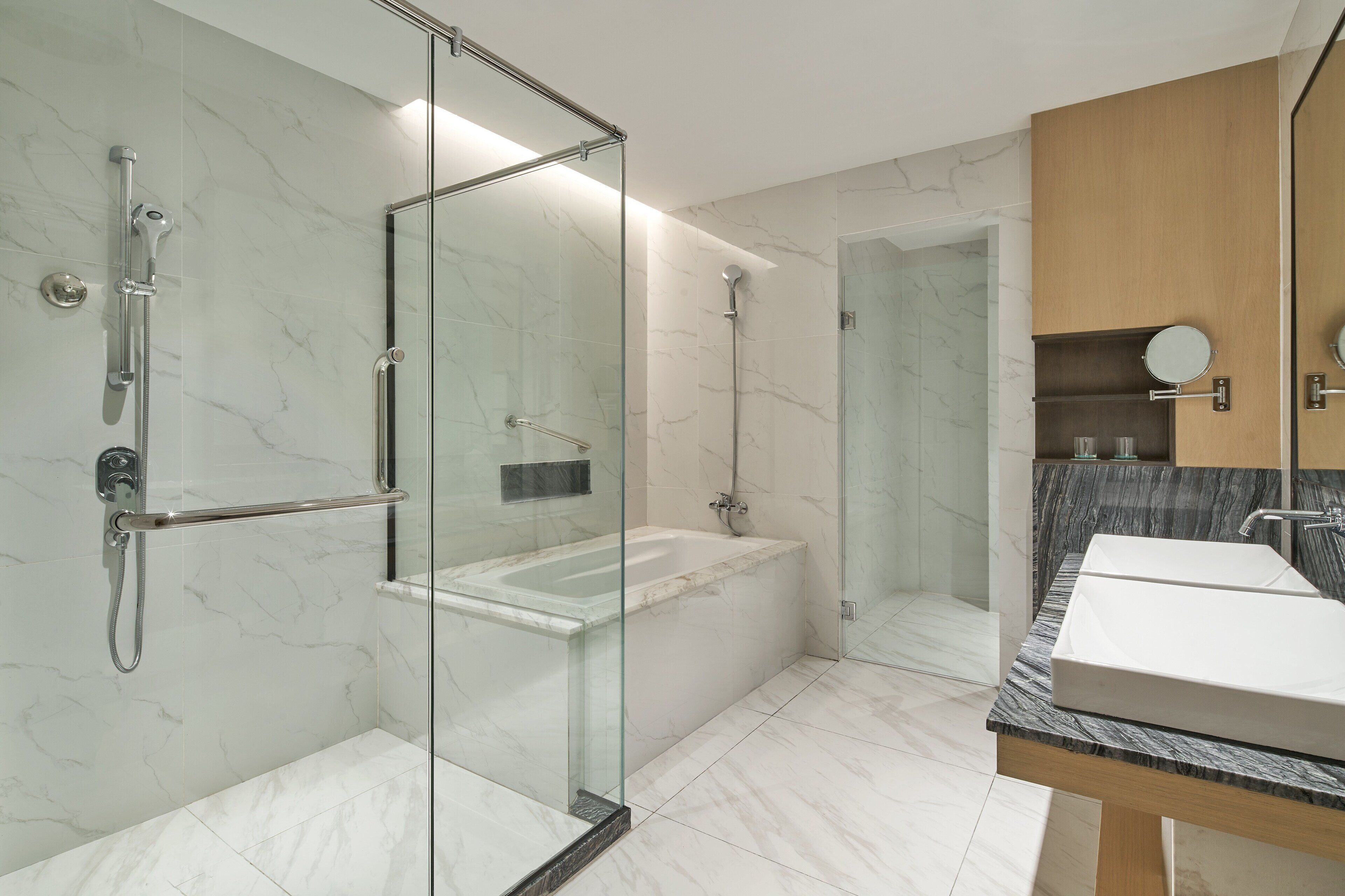 A modern bathroom with a glass-enclosed shower, a freestanding bathtub, and a vanity with two sinks.