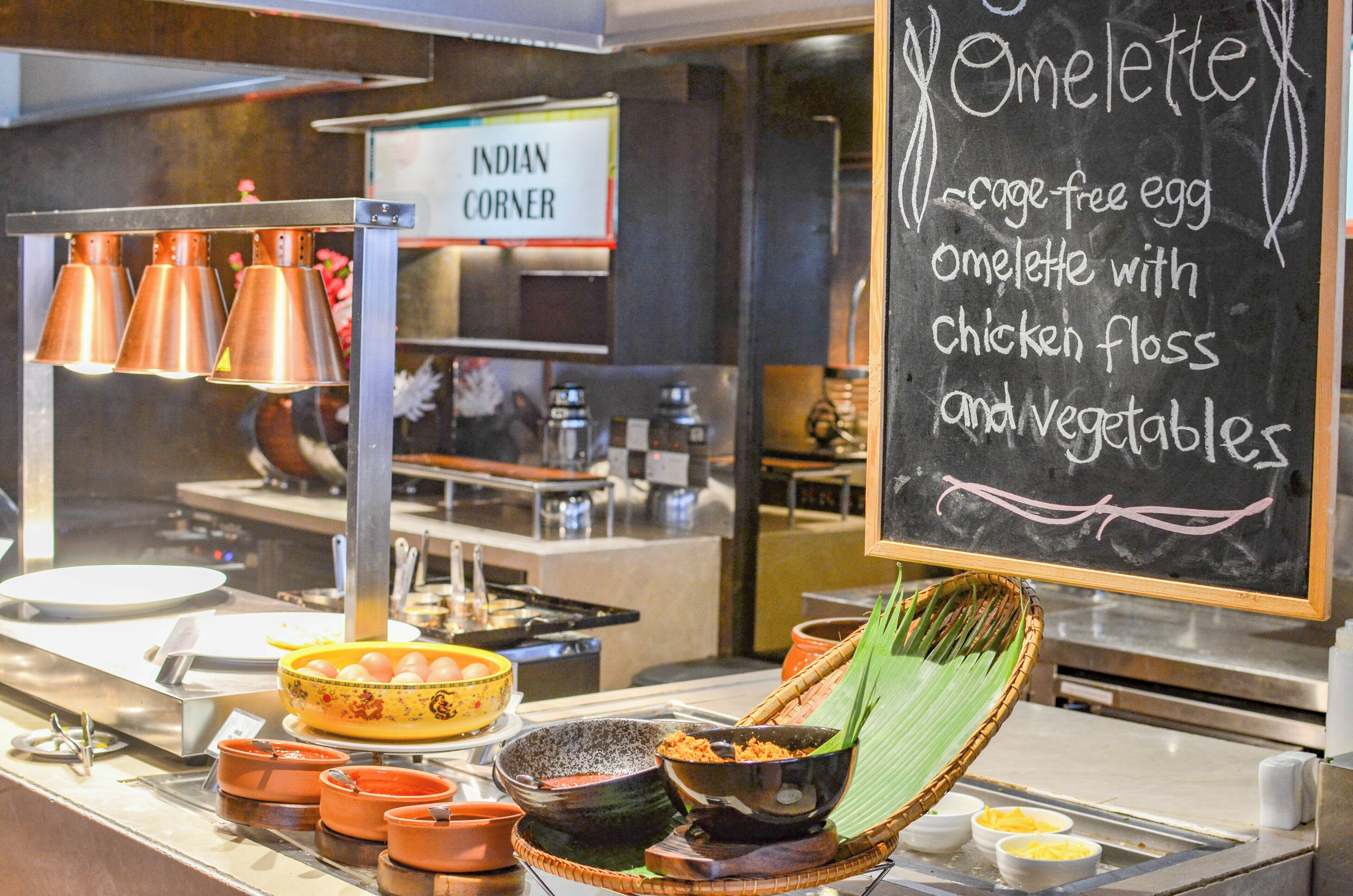 A buffet counter with a chalkboard menu listing an omelette option.