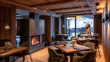 Un restaurante con interiores de madera, una chimenea de piedra y varias mesas para comer.