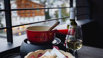 A table with a red pot, a bottle of wine, and a basket of bread.