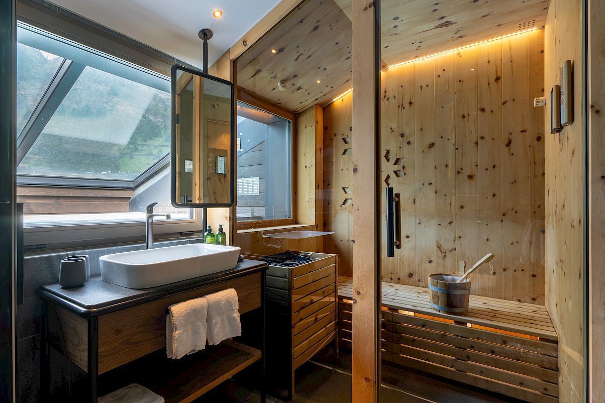 A modern bathroom with a skylight, wooden walls, a sink, and a sauna area.
