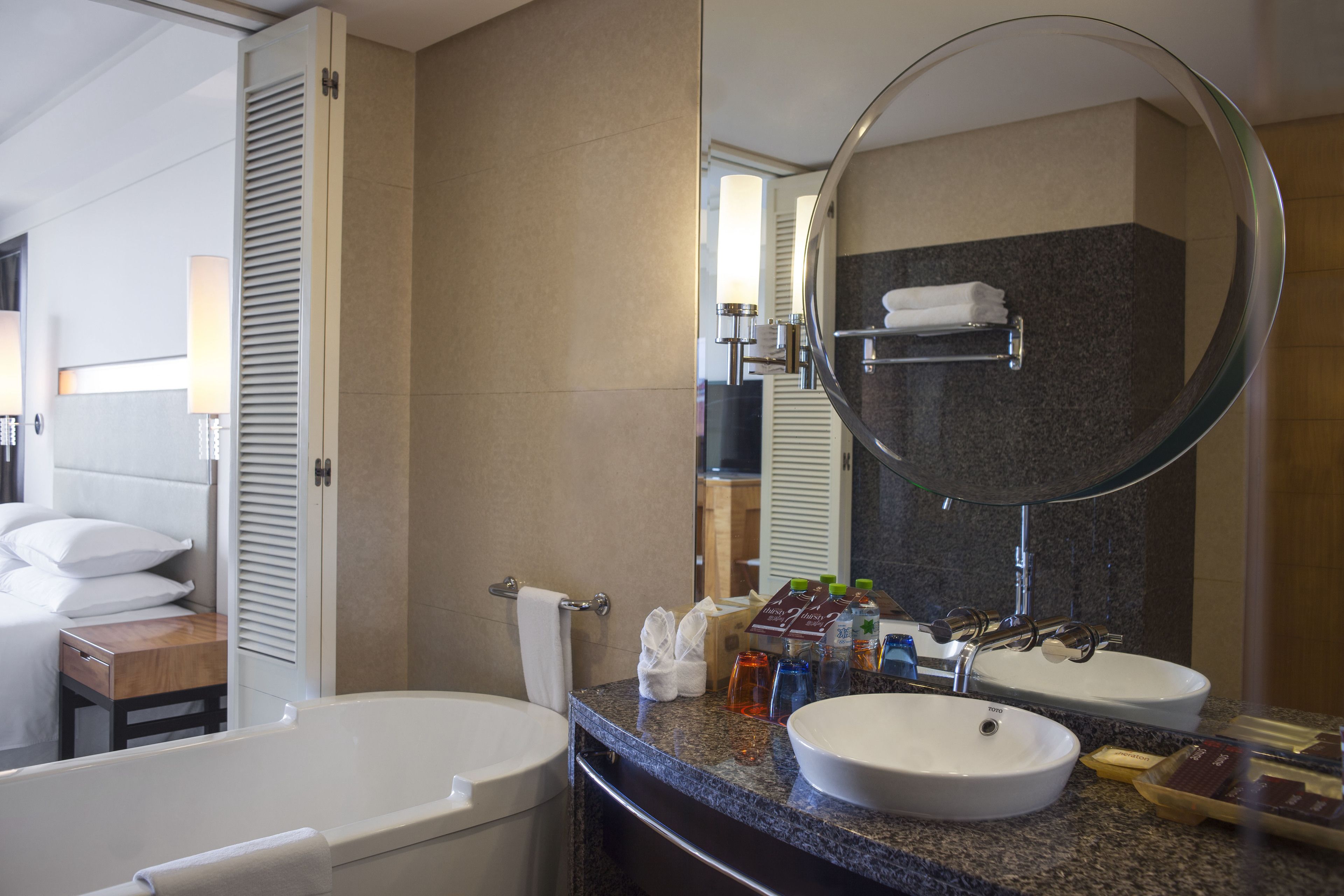 A modern bathroom with a bathtub, two sinks, and a large mirror.