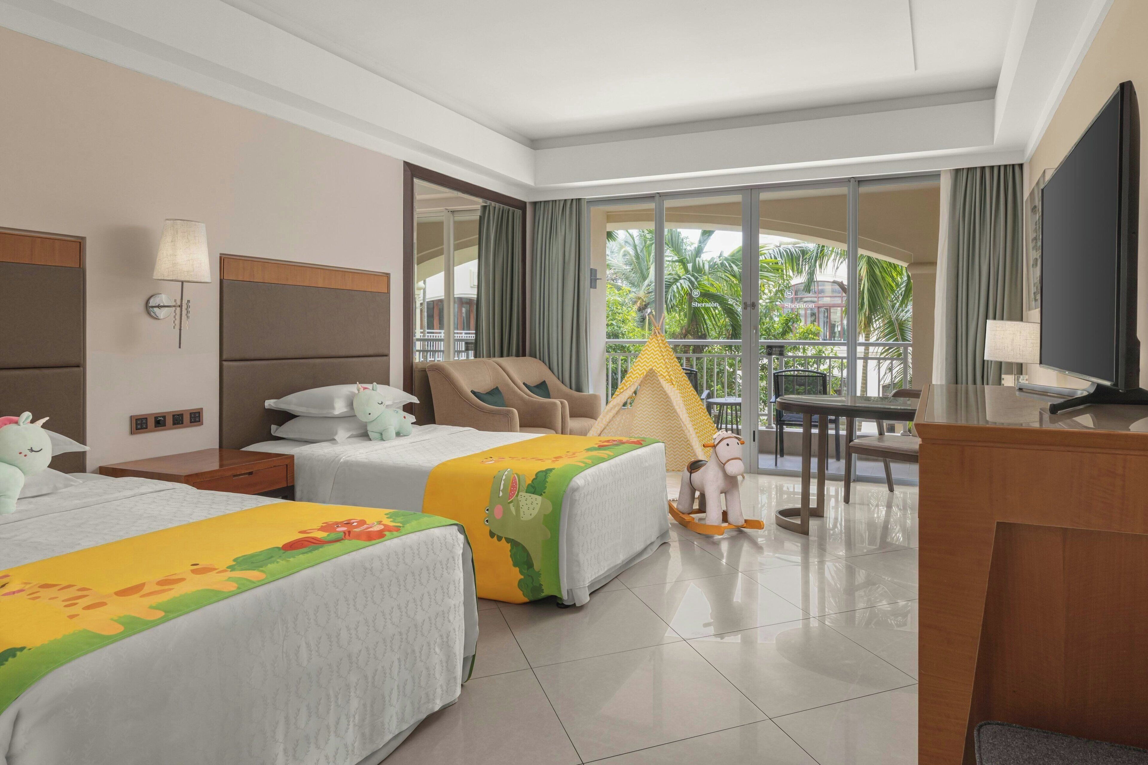 A hotel room with two beds, a desk, a chair, a TV, and a balcony with a view of palm trees.