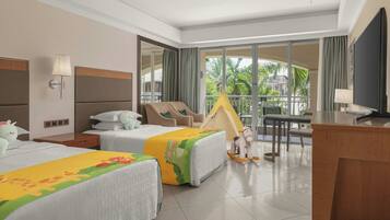 A hotel room with two beds, a desk, a chair, a TV, and a balcony with a view of palm trees.
