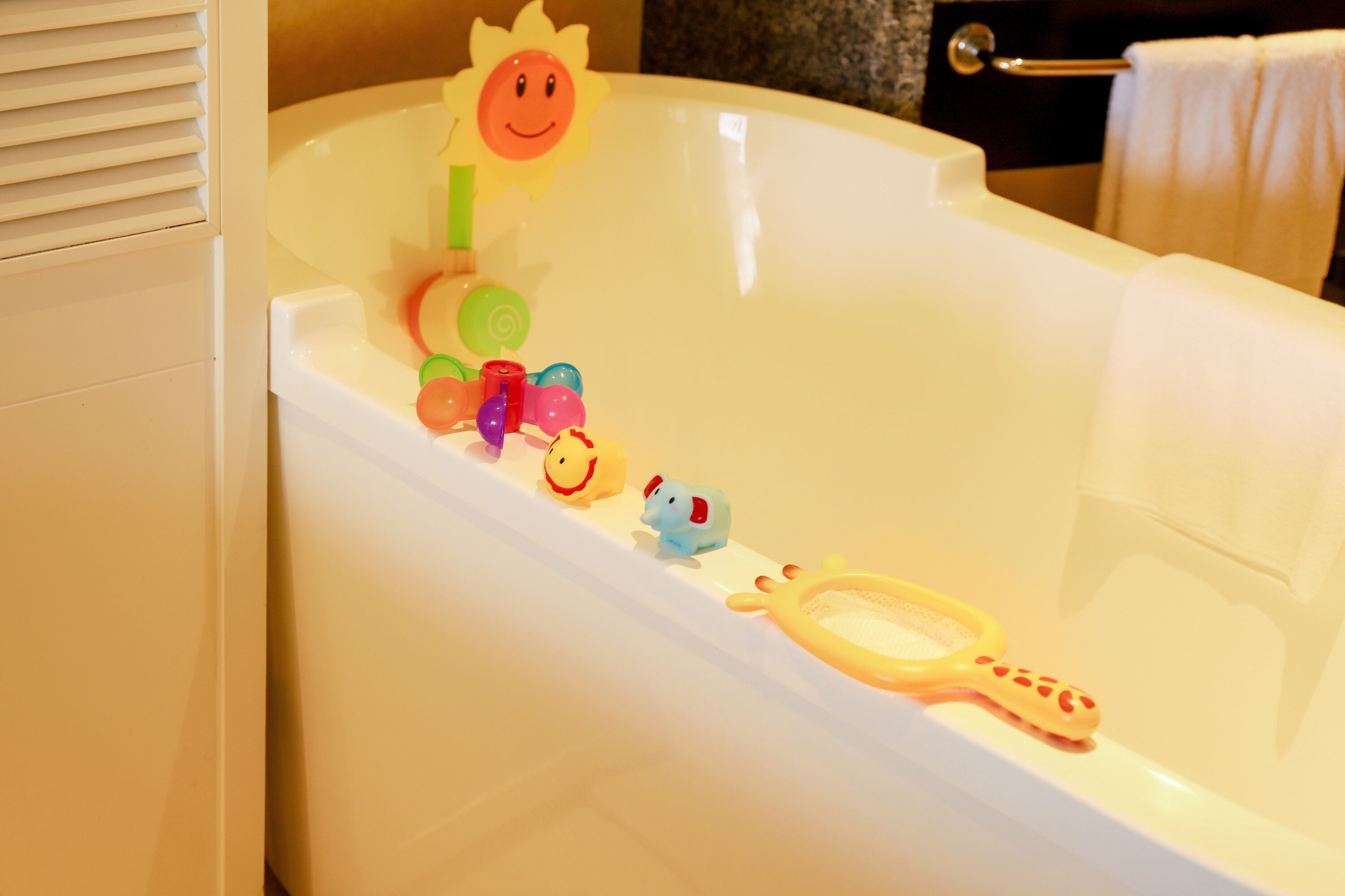 A bathtub with colorful bath toys and a sun decoration.