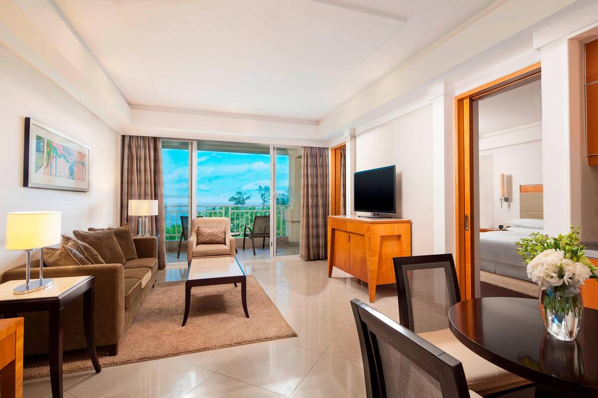 Una habitación de hotel moderna con balcón, televisión de pantalla plana, zona de comedor y cama.