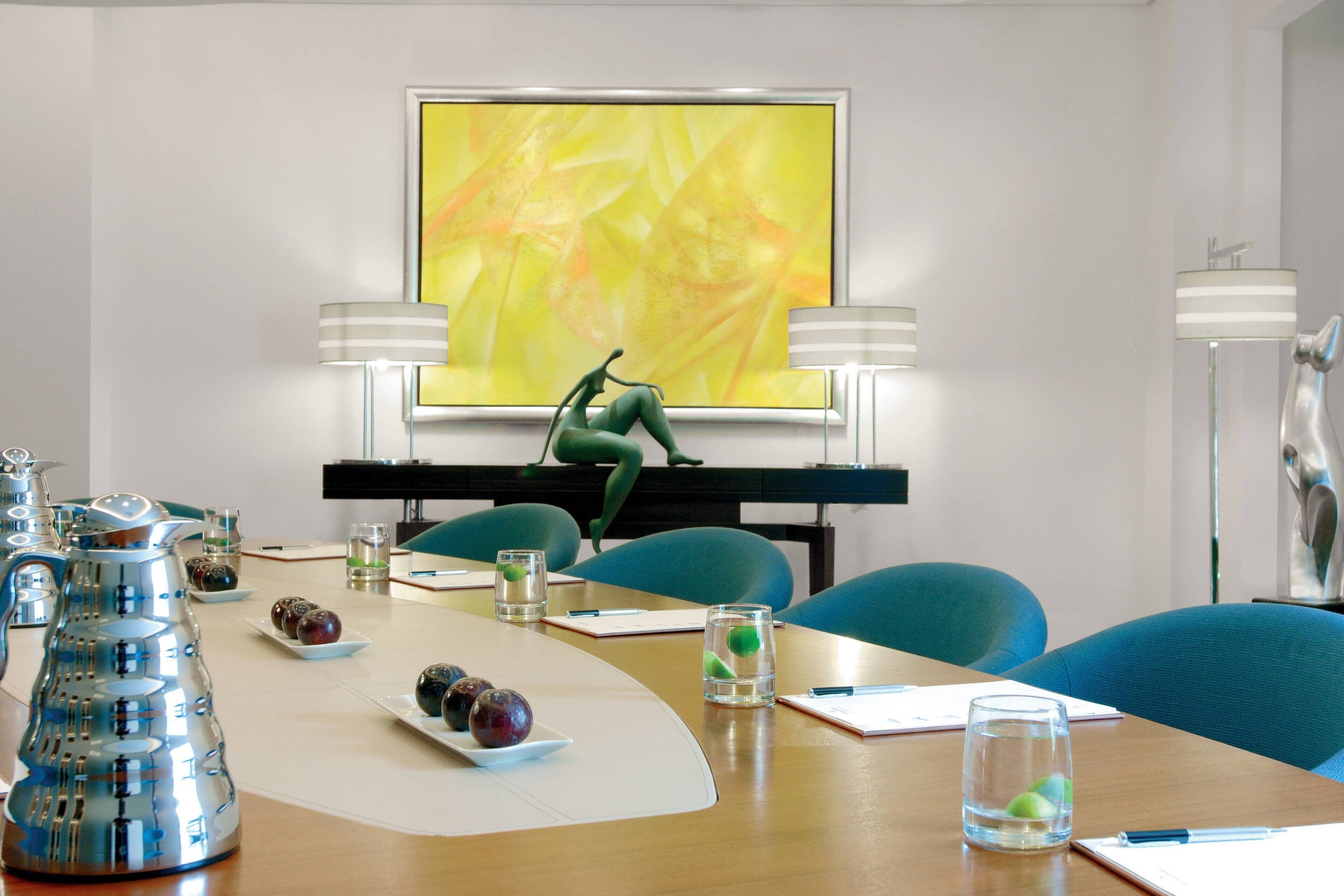 A conference room with a long table, chairs, a piano, and a large abstract painting on the wall.