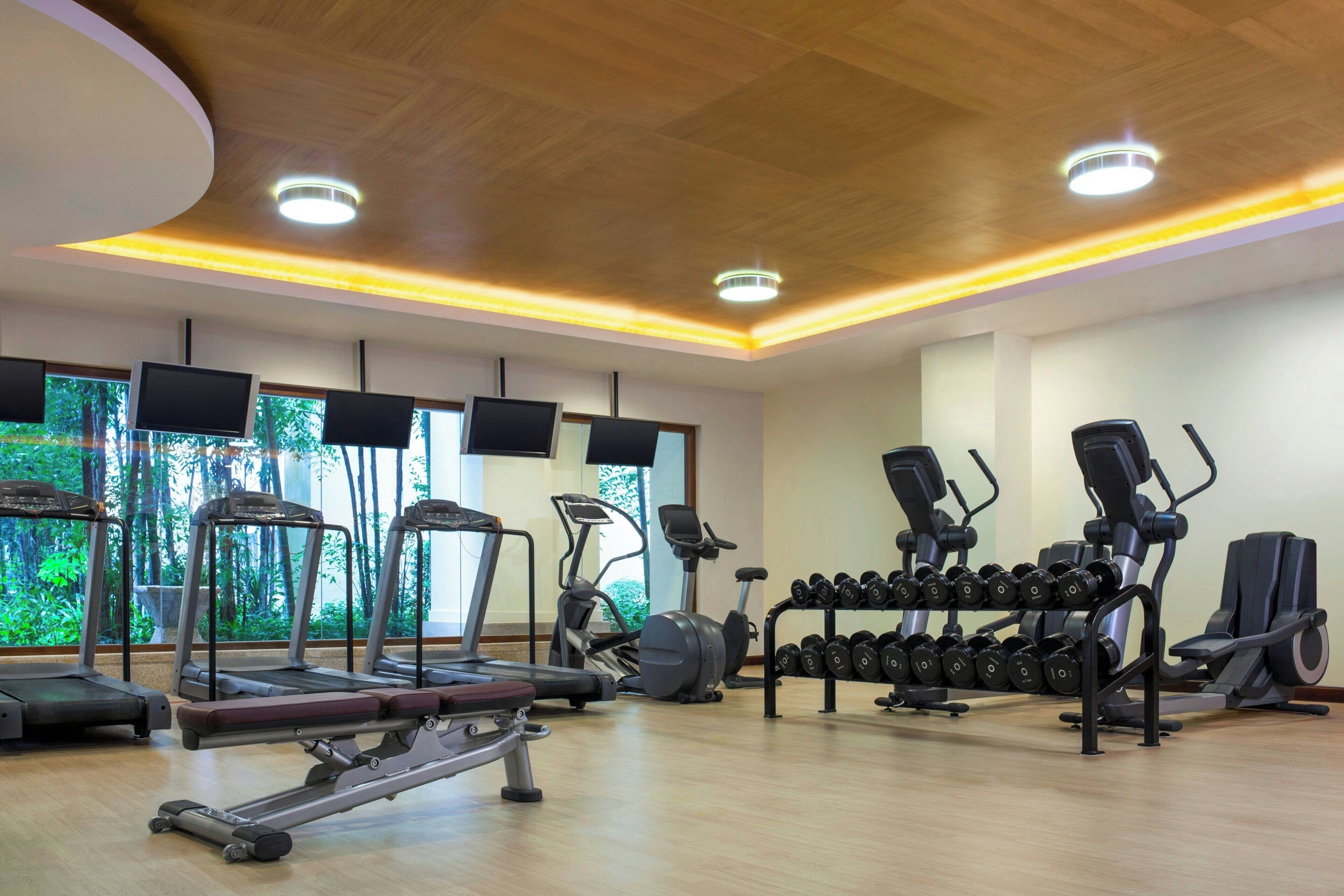 A gym with treadmills, elliptical machines, and dumbbells.