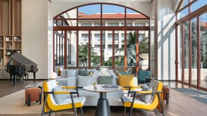 A modern living room with a grand piano, a sofa set, and a dining area with chairs and a table. - Sheraton Haikou Hotel (Haikou)