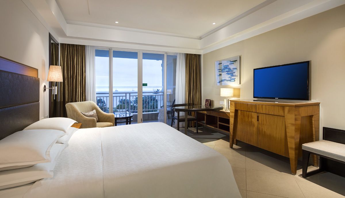 Une chambre d’hôtel avec un grand lit, un bureau, une télévision et un balcon avec vue.