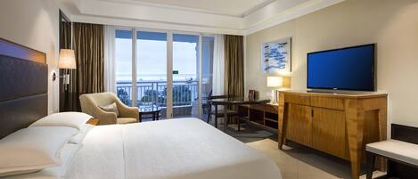 Une chambre d’hôtel avec un grand lit, un bureau, une télévision et un balcon avec vue.