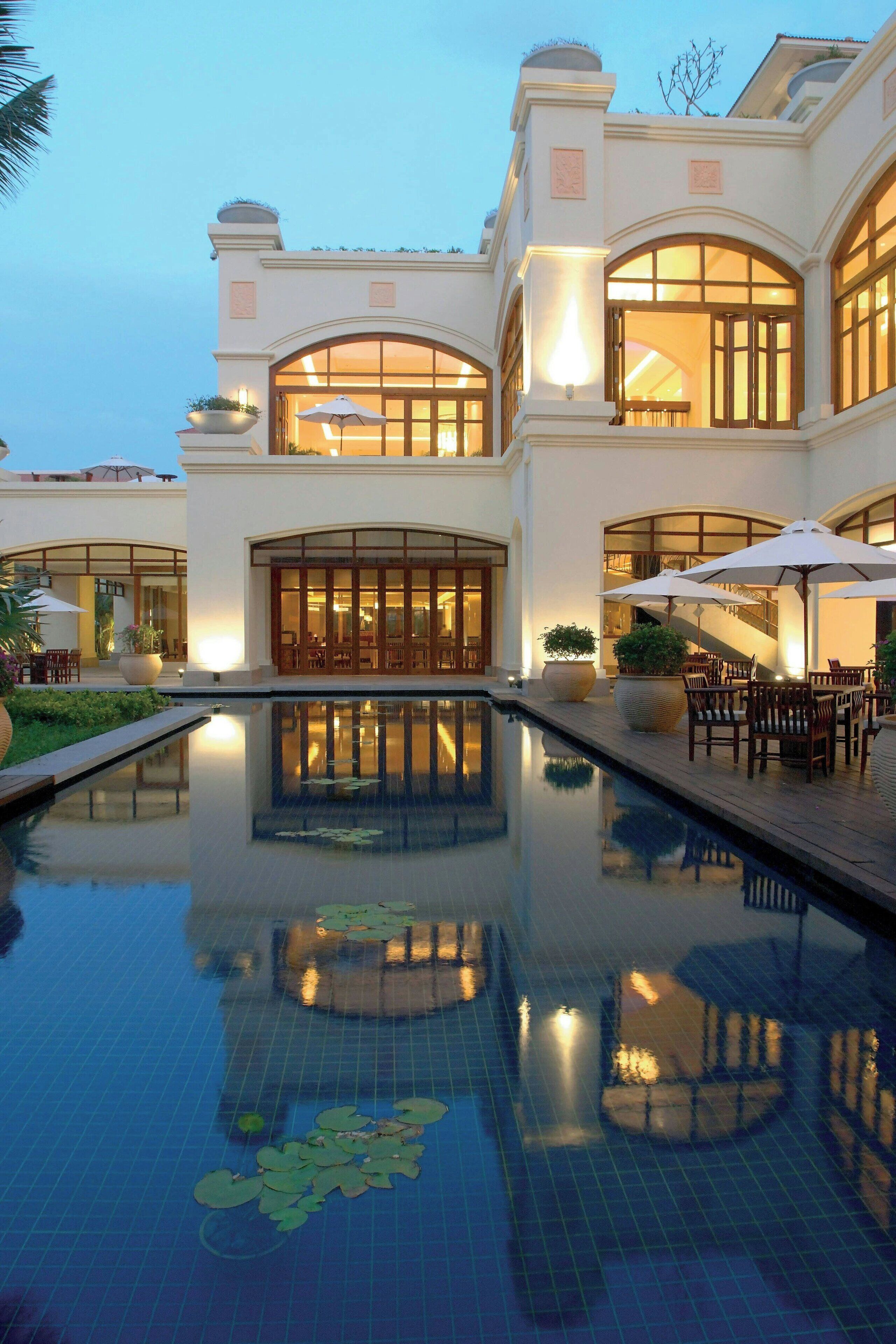 A luxurious hotel with a large pool, outdoor seating, and a grand entrance.