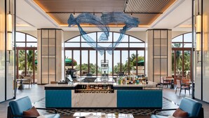 A modern bar area with a central island, seating arrangements, and large windows offering views of the outdoors. - Sheraton Haikou Hotel (Haikou)