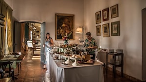 Un comedor con una larga mesa dispuesta para una comida, una araña y cuadros en la pared.