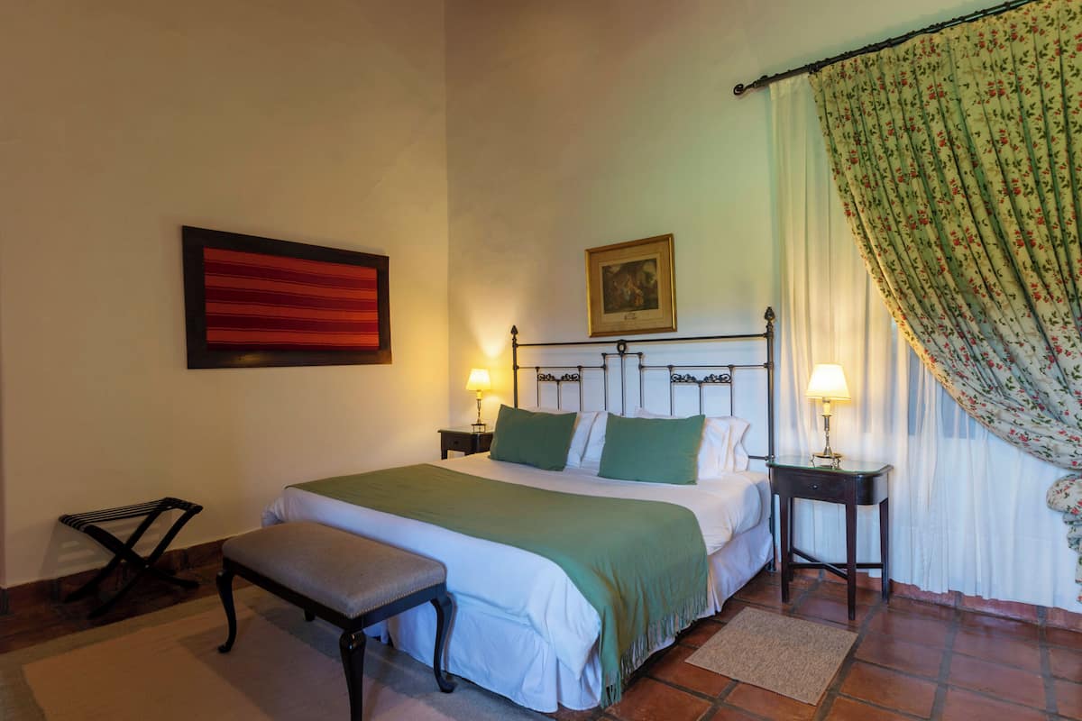 A neatly arranged bedroom with a bed, bedside tables, a bench, and a picture on the wall.