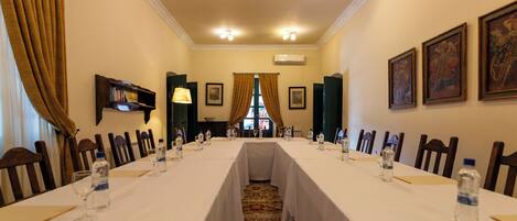 A conference room with a long table, chairs, water bottles, and framed pictures on the walls.