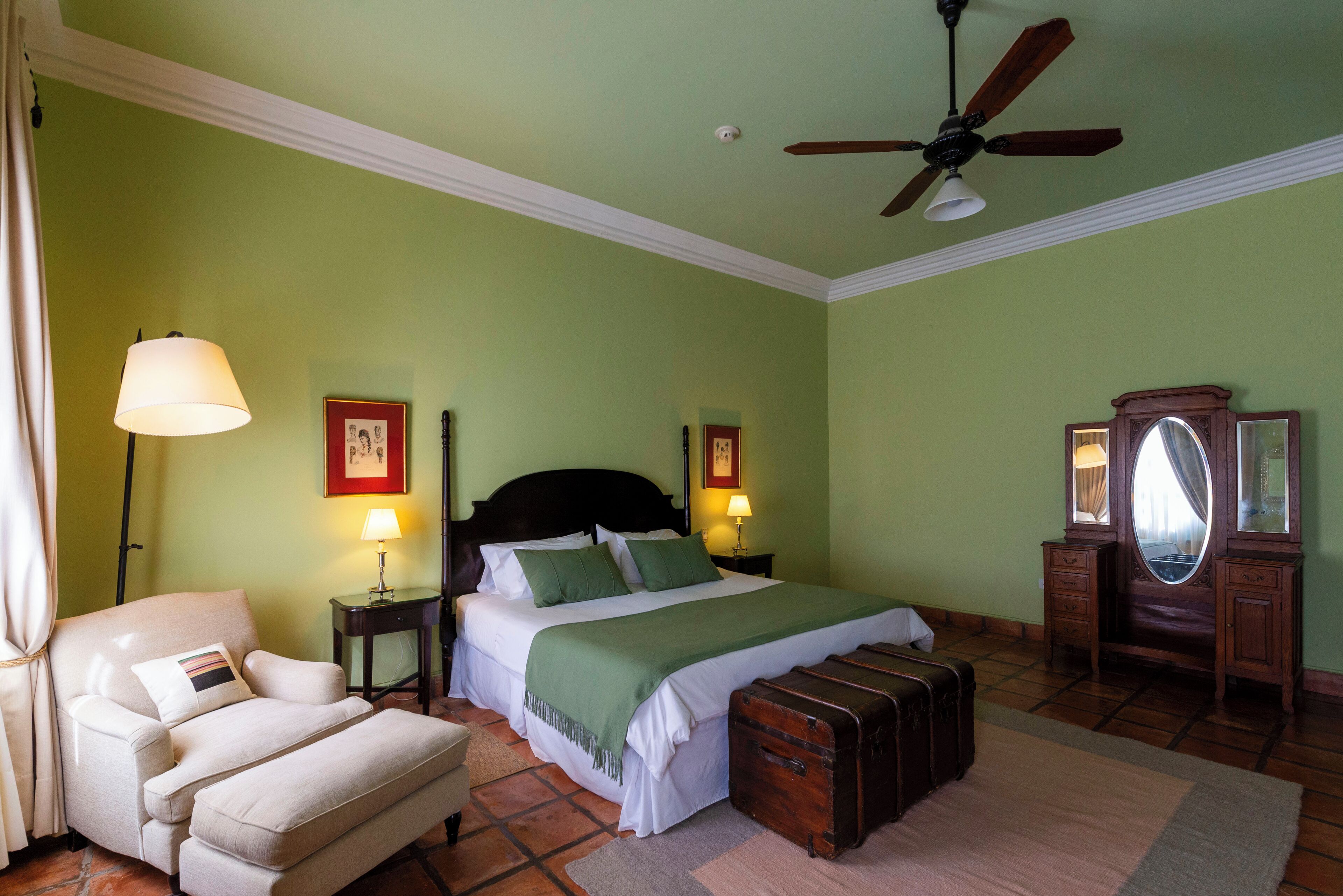 A bedroom with a bed, a chair, a dresser, and a ceiling fan.