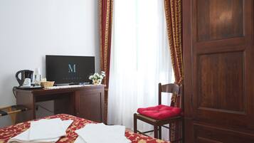 Ein Hotelzimmer mit Bett, Schreibtisch mit Fernseher, Stuhl und Kleiderschrank.