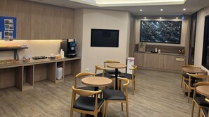 Un café moderne avec des meubles en bois, une machine à café et un grand tableau accroché au mur.