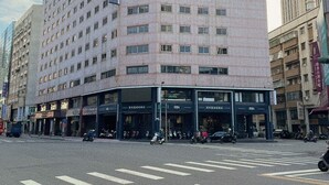 Un hôtel à plusieurs étages, doté d’une façade moderne, situé à un carrefour.