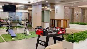 Un hall d’hôtel équipé d’un baby-foot, de matériel d’exercice et d’un téléviseur.
