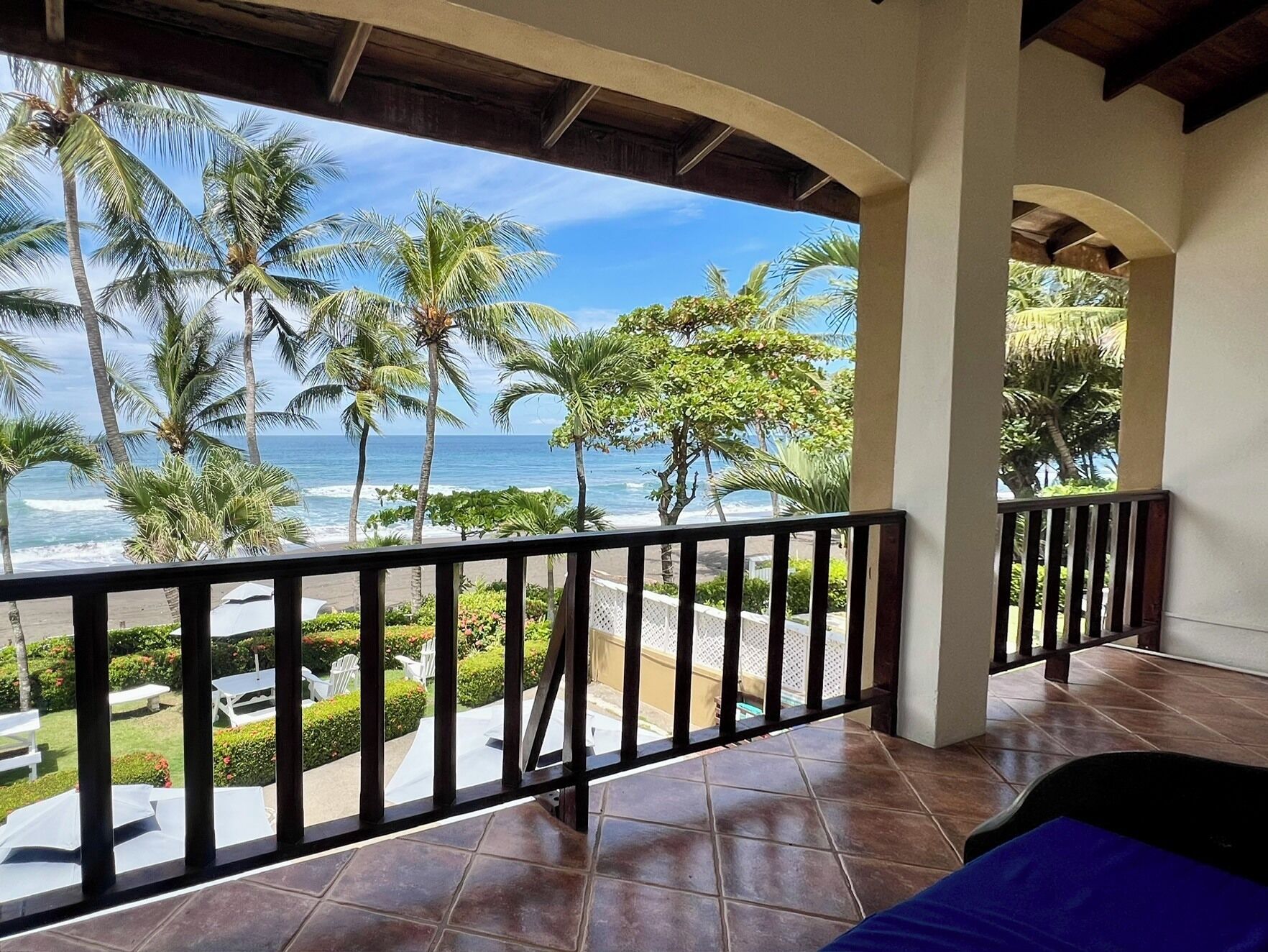 A balcony with a view of the ocean and palm trees.