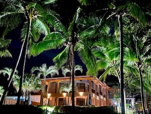 A multi-story building surrounded by palm trees at night. - The Backyard Hotel (Jacó)
