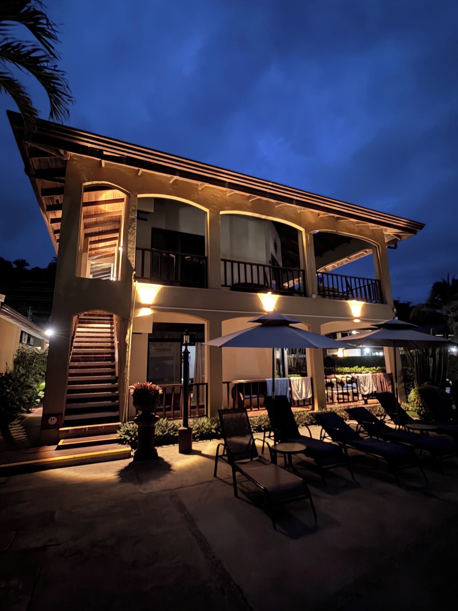 A two-story building with a balcony, outdoor seating area, and a staircase leading to the entrance.