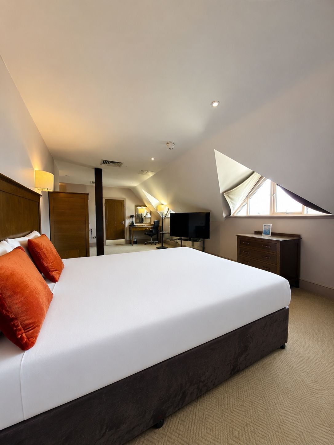 Una habitación de hotel con una cama grande, un escritorio, un televisor y una ventana.