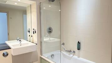 A modern bathroom with a glass-enclosed shower, a white sink, and a bathtub.