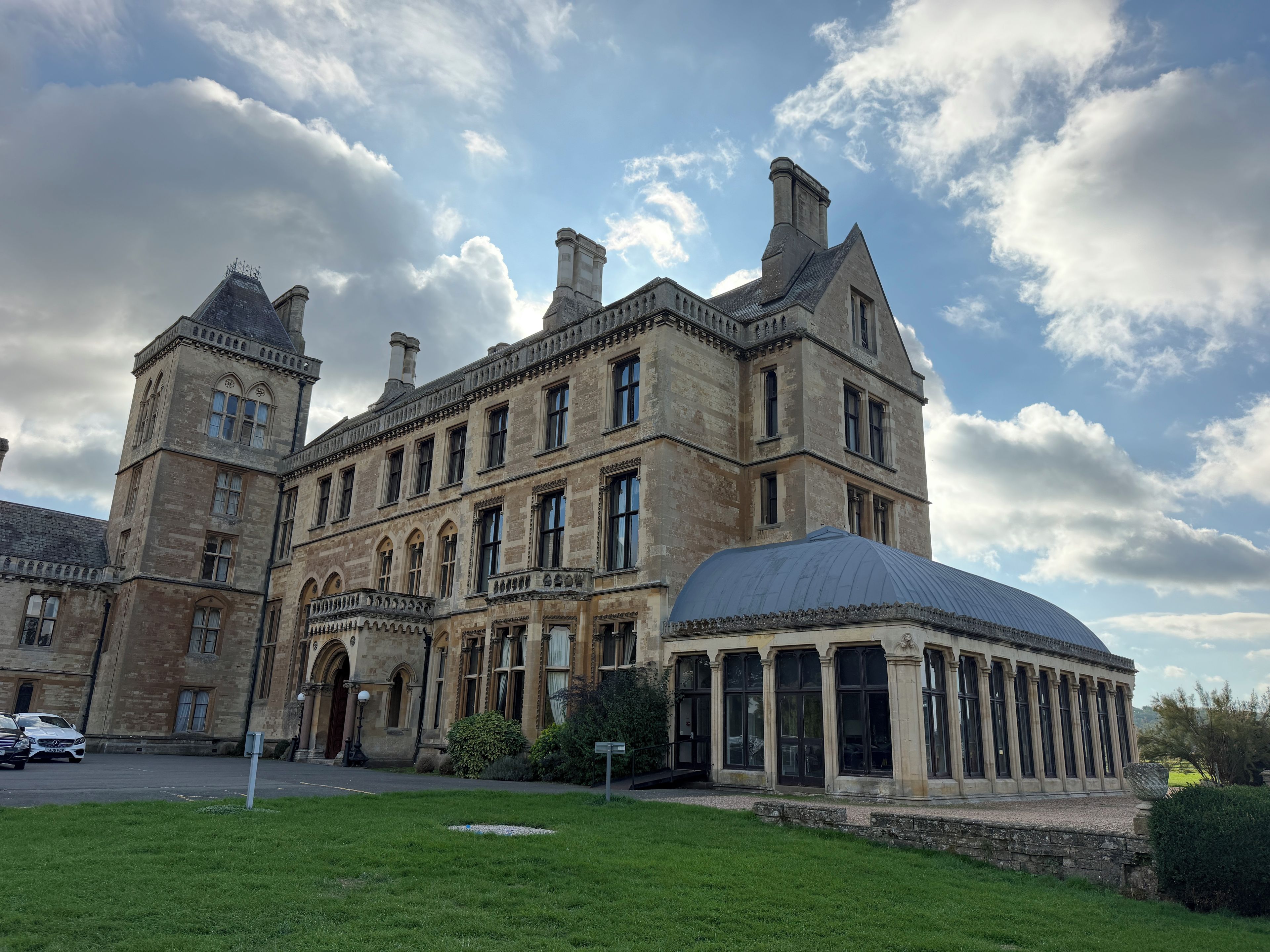 A historic building with a prominent tower, a large central section with multiple windows, and a covered pavilion.