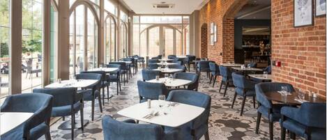 Un restaurante con pared de ladrillo, ventanas amplias y suelo de patrón hexagonal.