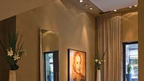 Een moderne lobby met een grote spiegel, een ingelijst kunstwerk en een receptiebalie.