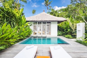 A poolside area with a thatched-roof structure, surrounded by lush greenery. - COMO Uma Ubud (Ubud)