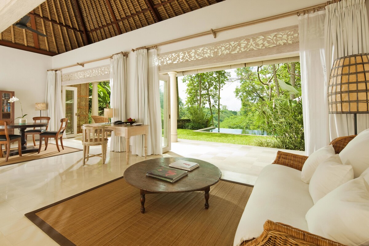 A spacious living area with a large window, a dining table, and a sofa.