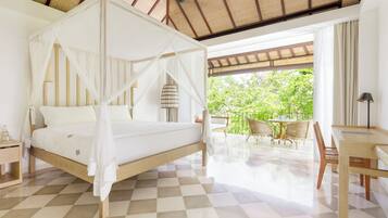 A bedroom with a four-poster bed, a wooden desk, and a view of greenery outside.