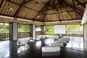 Una habitación amplia con techo alto y ventanas grandes, que ofrece vistas al exterior con vegetación.