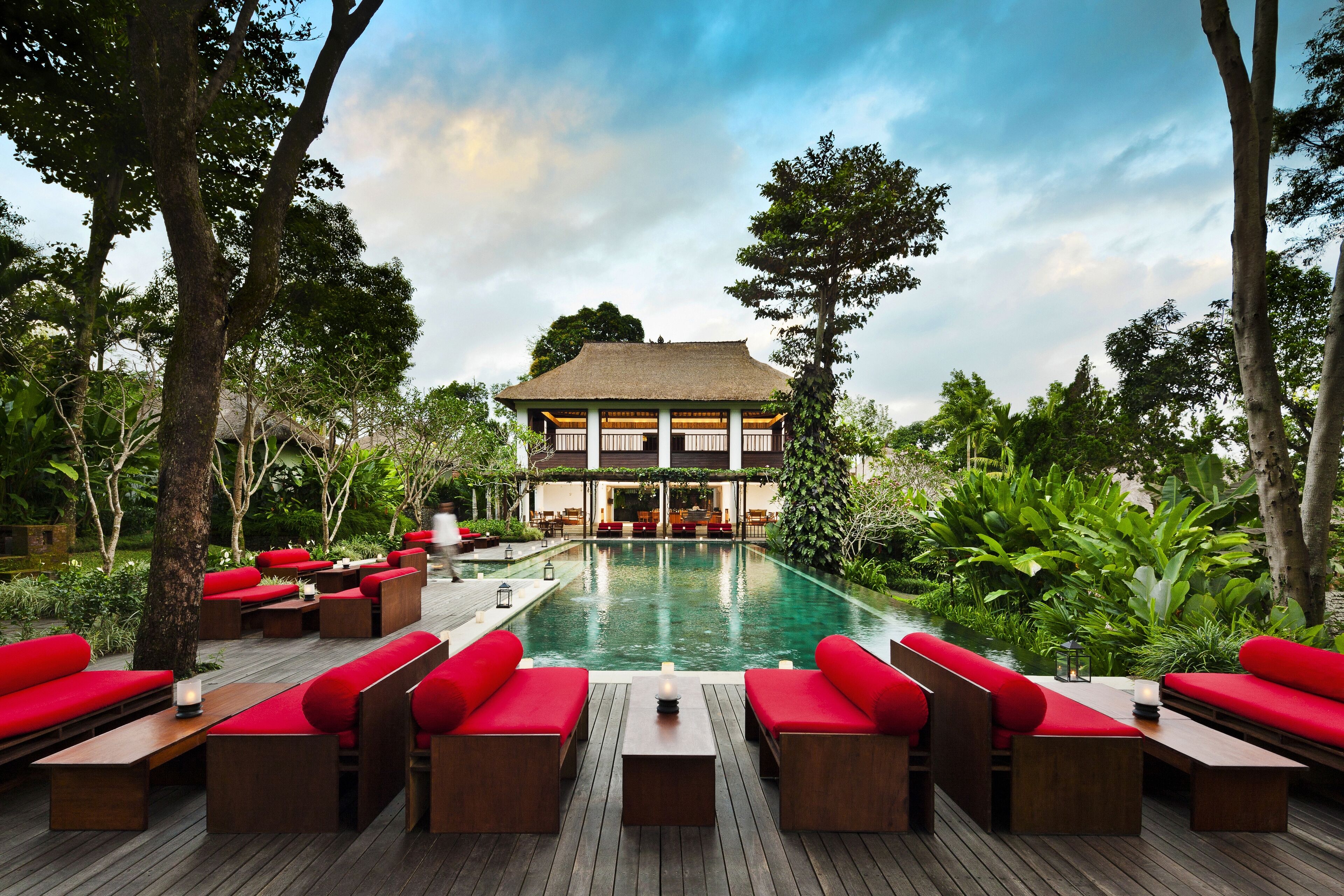 A poolside area with wooden deck seating and a pool in the background.