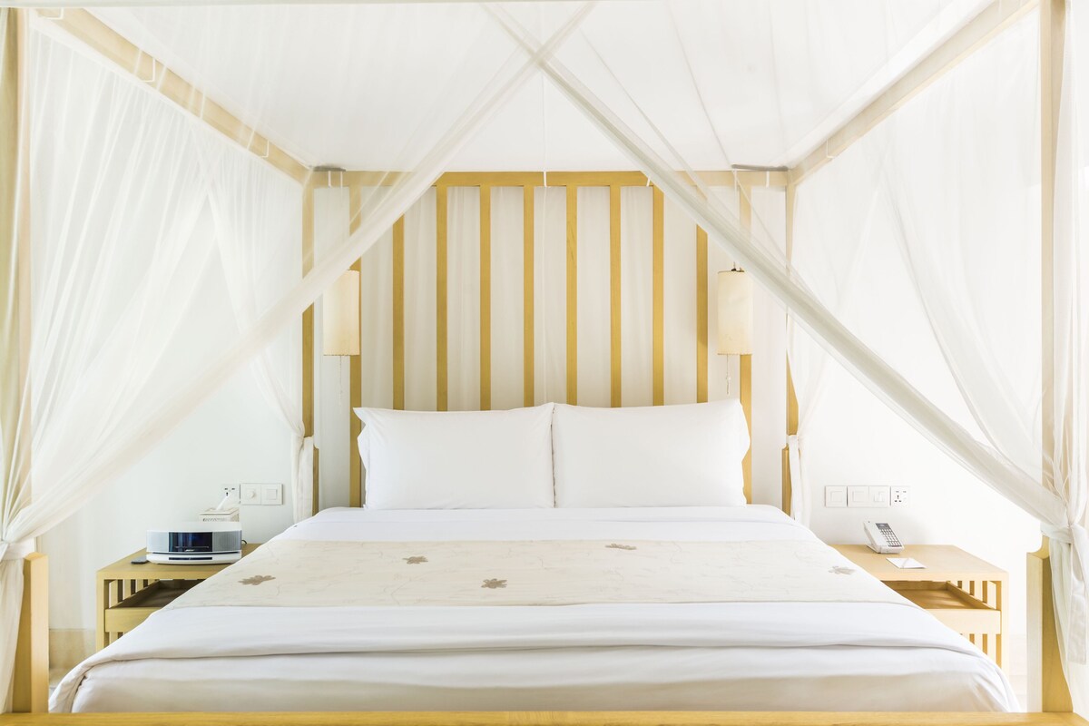 A bed with a canopy, a bedside table, and a nightstand.