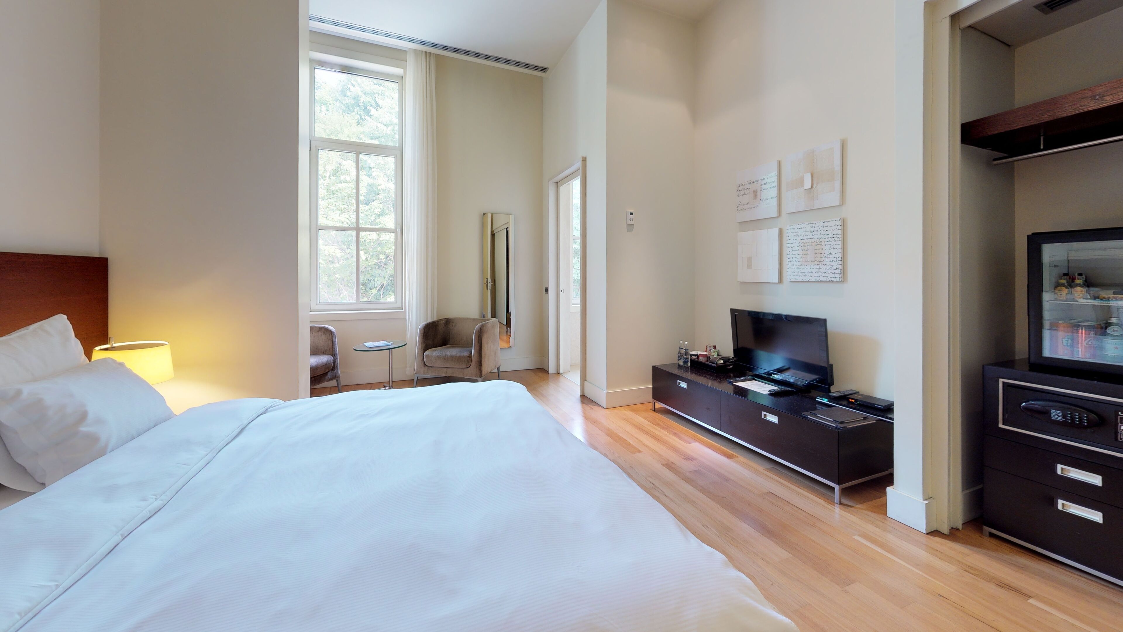Una habitación de hotel moderna con una cama grande, un televisor, una mesita y una zona de estar.