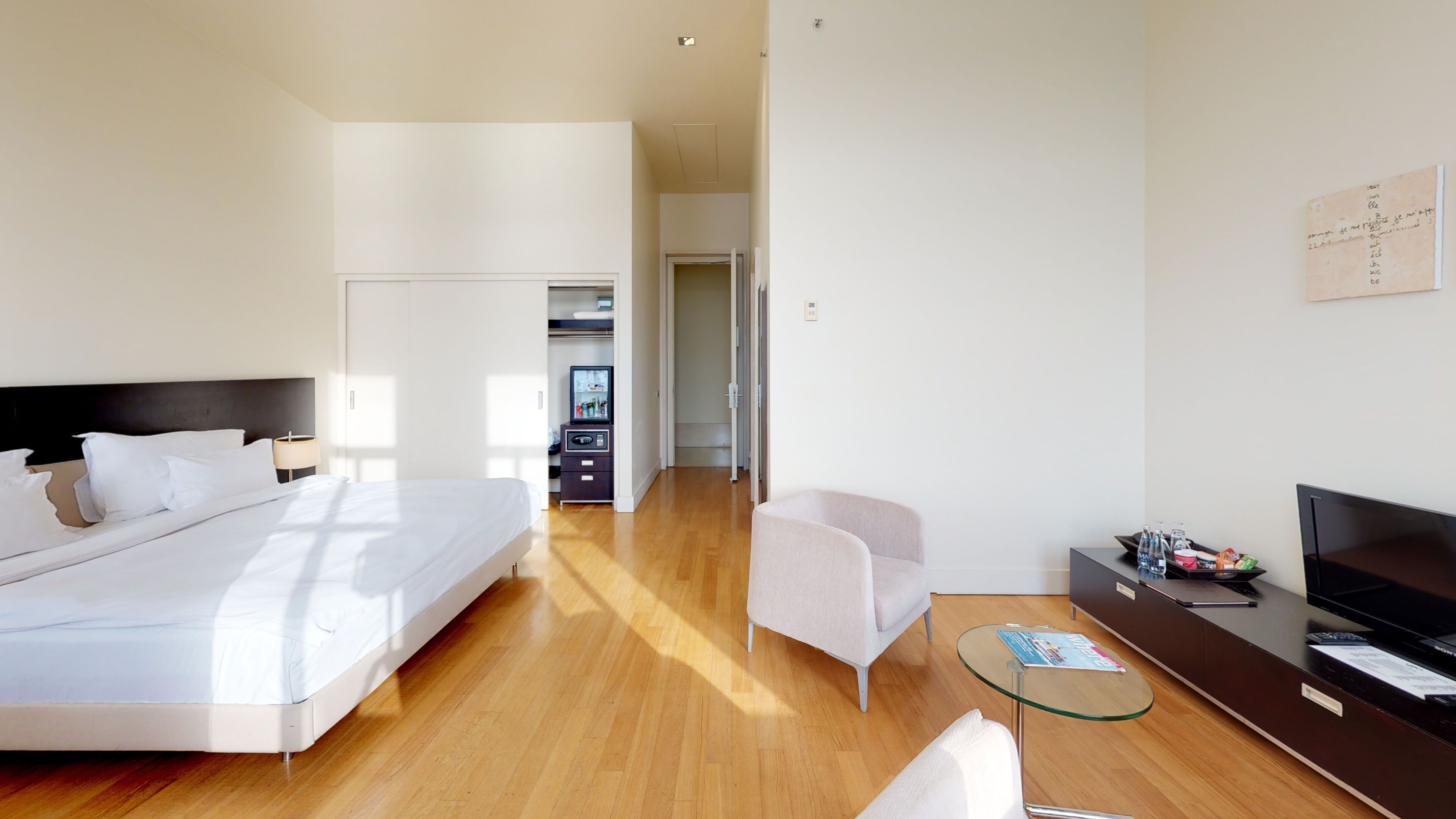 Una habitación de hotel moderna con una cama, una zona de estar, un televisor y una pequeña mesa.