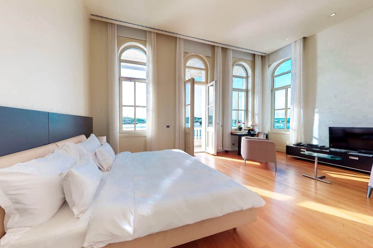 A spacious bedroom with a large bed, a desk, and a TV.