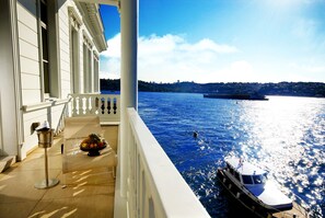 Ein Balkon mit Blick auf einen Fluss, ein Boot und eine entfernte Skyline.