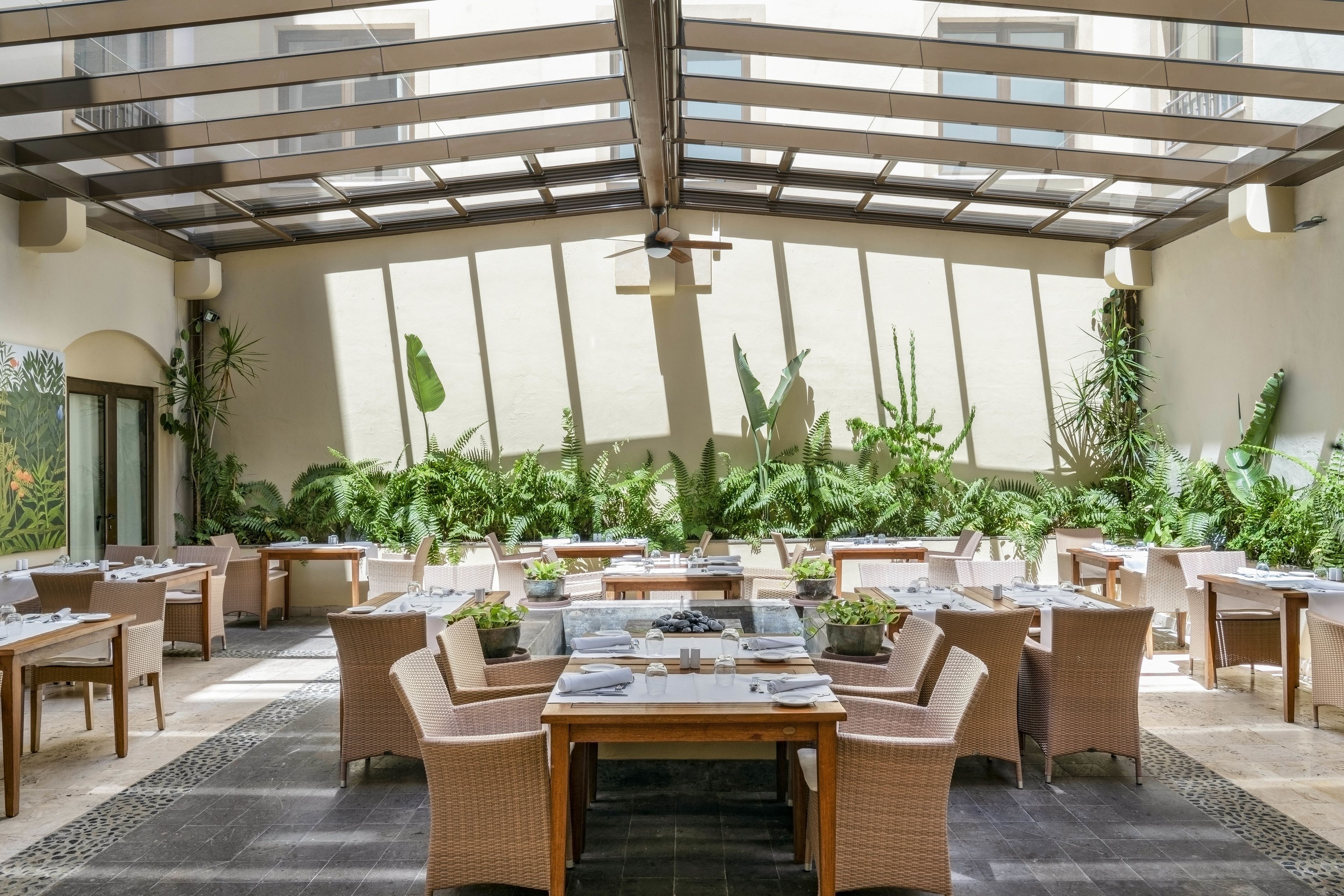 A covered outdoor dining area with wicker furniture and potted plants.