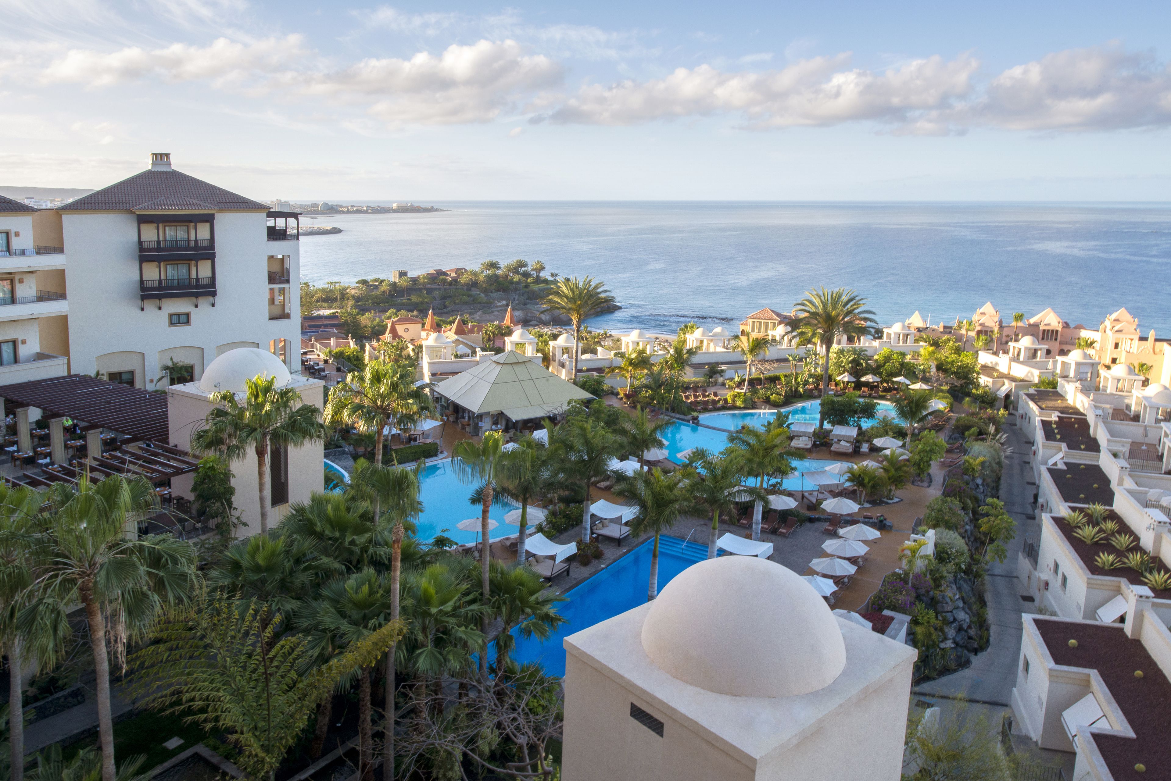 Un resort con una piscina grande, palmeras y vista al océano.