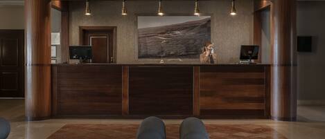 Una recepción con un cuadro de paisaje grande, paneles de madera y un diseño moderno.